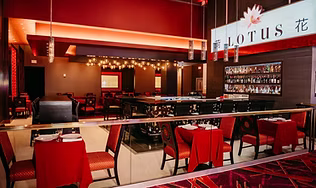 The elegant, red and black interior dining room and bar area of the LOTUS Chinese restaurant, representing the refined fine dining experience with Cantonese and Sichuan specialties.