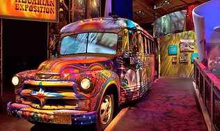 A brightly painted, psychedelic "hippie" bus displayed inside the museum, representing the immersive exhibits celebrating 1960s, Woodstock, and American counter-culture.