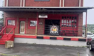 The exterior of the red brick building housing the independent craft brewery, featuring industrial-style doors, representing the local brew stop known for its 16 rotating taps and diverse craft beer selection.