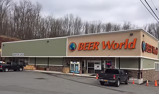 The exterior of the 'Beer World' store in Monticello, a large commercial building with a prominent orange sign, representing the top beverage stop for an extensive selection of craft beers, hard seltzers, and local favorites.