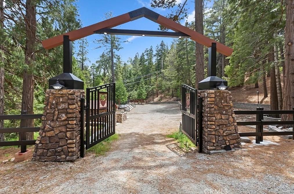 Rustic stone and timber entrance gate opening onto a wooded path, representing the secluded, nature-focused retreat center in Monticello, ideal for concerts, retreats, and events.