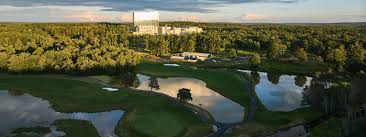Aerial view of the championship golf course in Monticello, featuring lush green fairways and scenic water hazards surrounded by dense forest, highlighting the beautiful and challenging scenery near the resort.