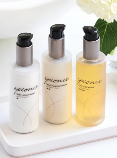 Three Epionce brand cleanser bottles (Milky Lotion Cleanser, Gentle Foaming Cleanser, Lytic Gel Cleanser) on a white tray with a white flower in the background at Becker Cosmetic featuring Skincare services