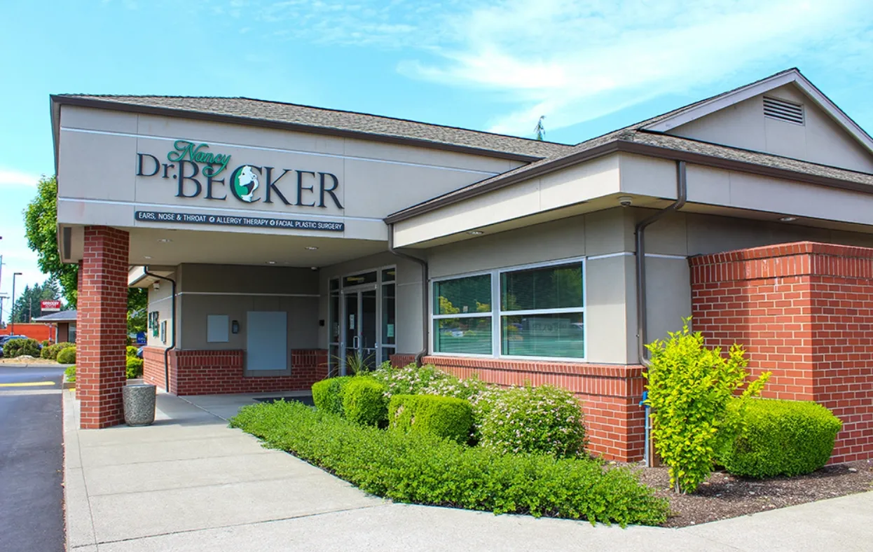 Exterior view of the Dr. Nancy Becker cosmetic clinic with lush landscaping under a blue sky at Becker Cosmetic featuring cosmetic treatment services Bonney Lake, WA