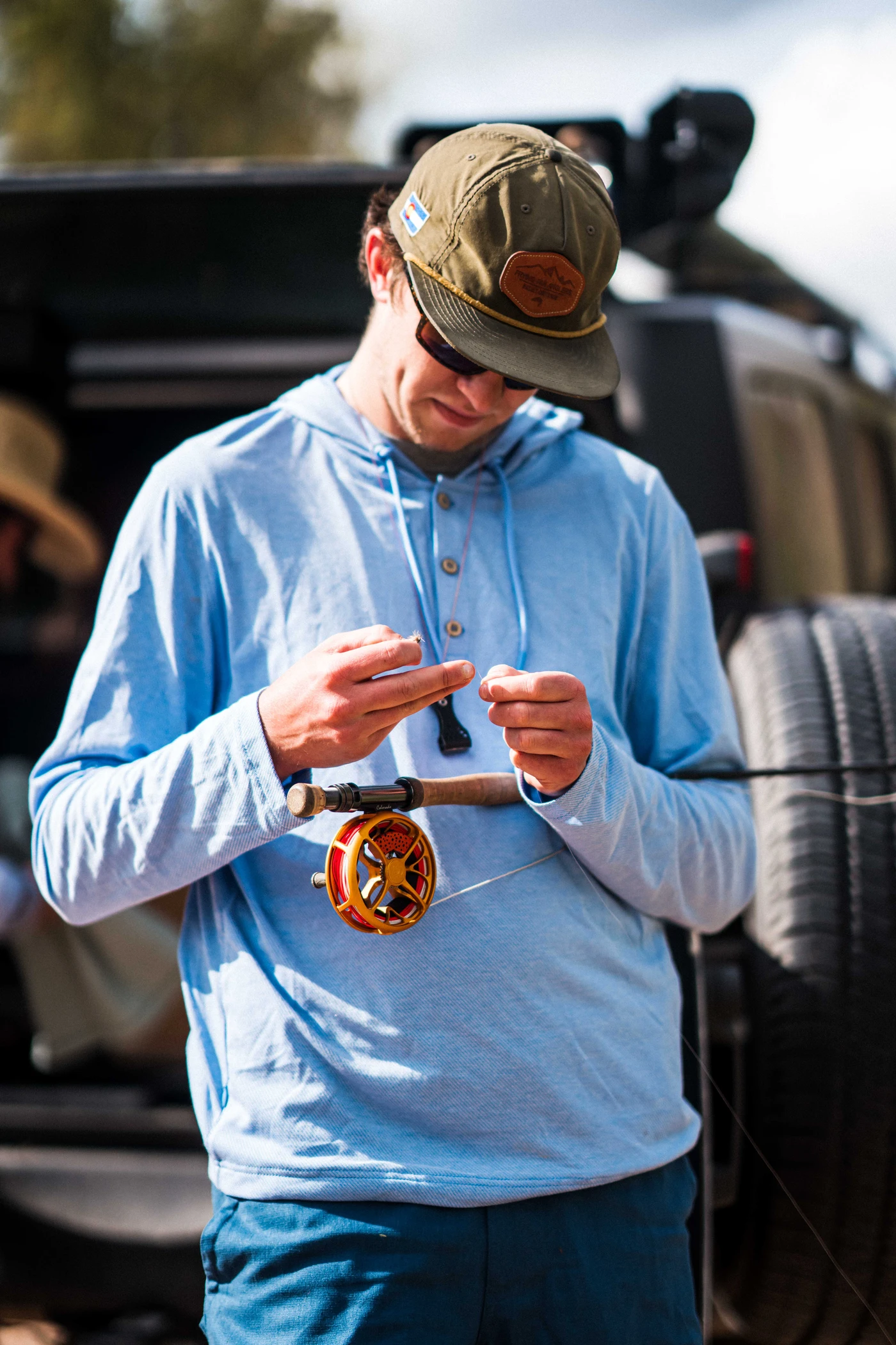 Man wearing a cap, dark sunglasses, and a neck gaiter on a boat, with water and sky in the background.