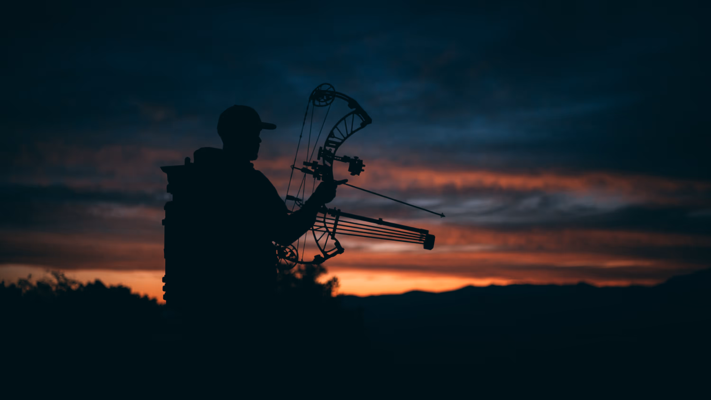 Close-up view of binoculars mounted on a tripod with a blurred desert landscape and sunrise in the background.