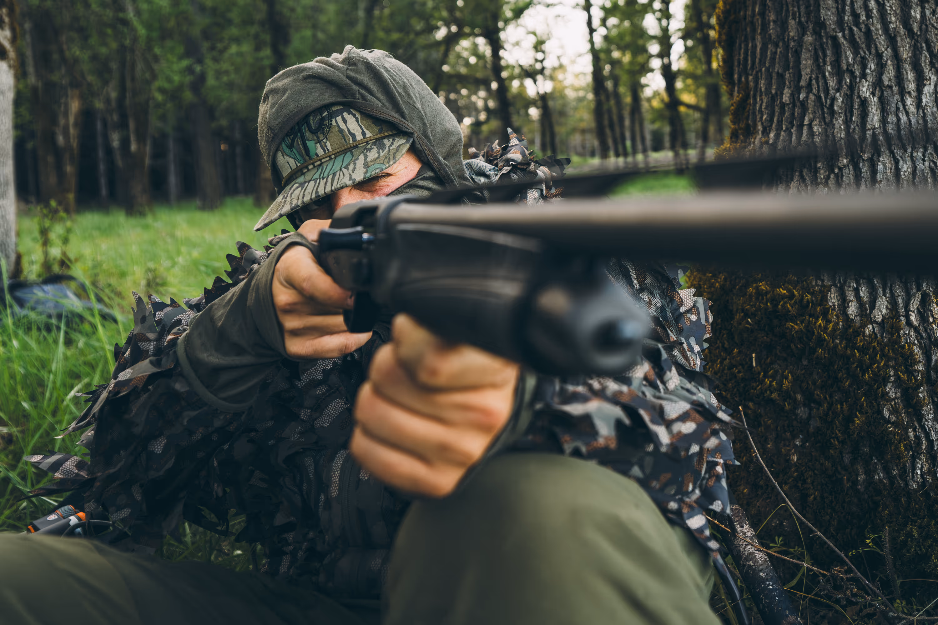 Two gray Pelican brand hard-shell cases, one large and one smaller, standing on grass in front of a weathered red rusty metal wall.