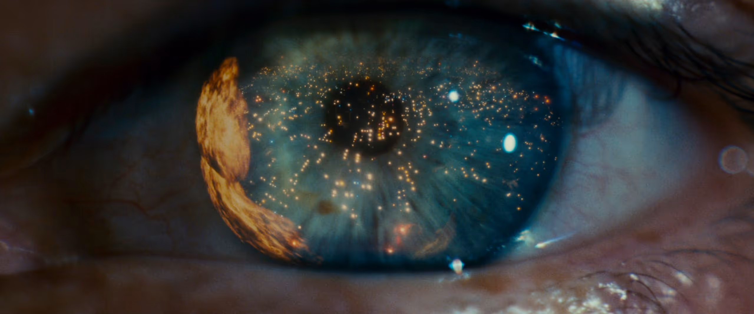 Close-up of a blue eye with a reflection of glowing city lights and a fiery orange object.