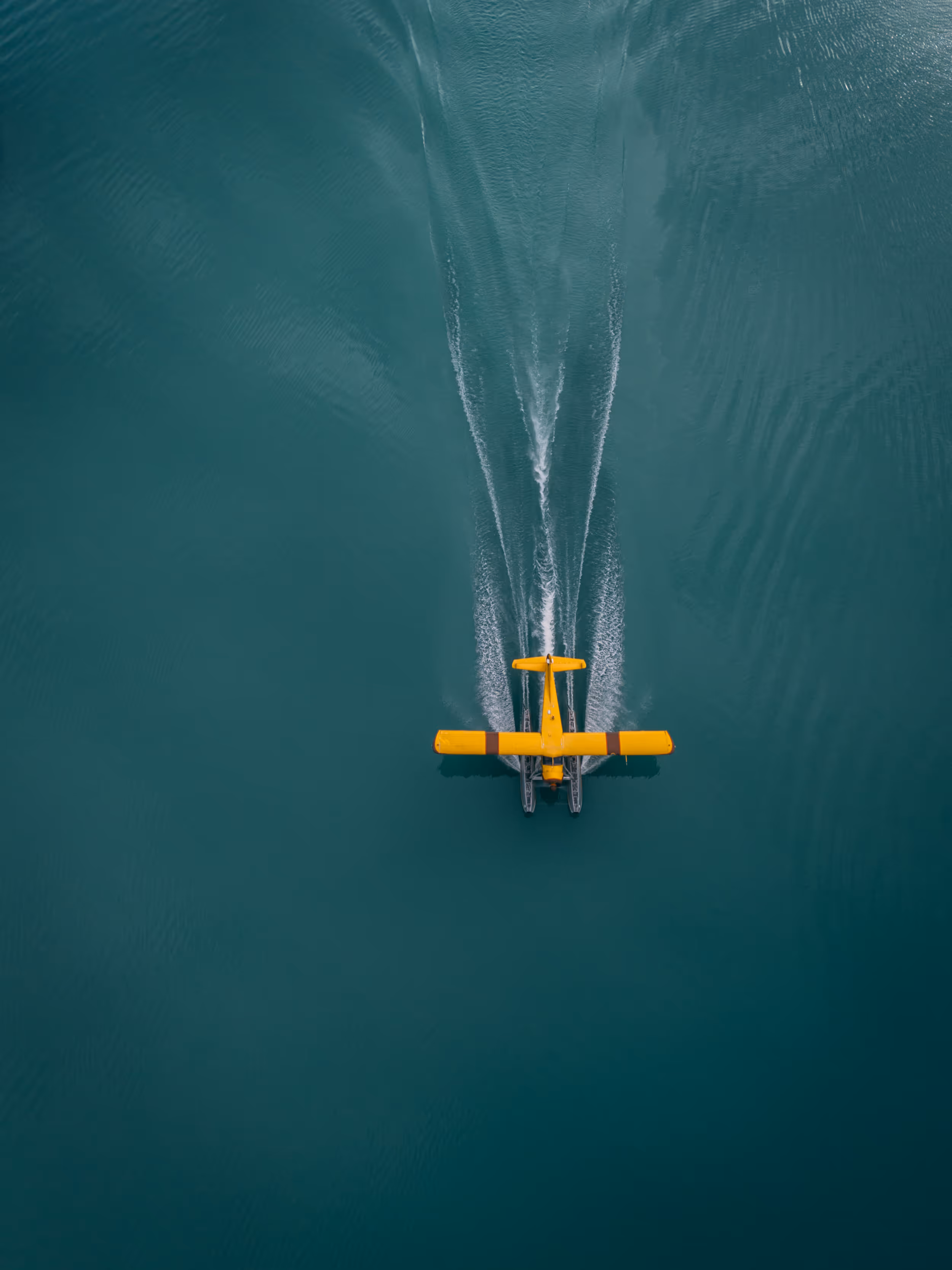 Pickup truck with rooftop camper parked on a hill at sunset with a person standing nearby overlooking mountains.