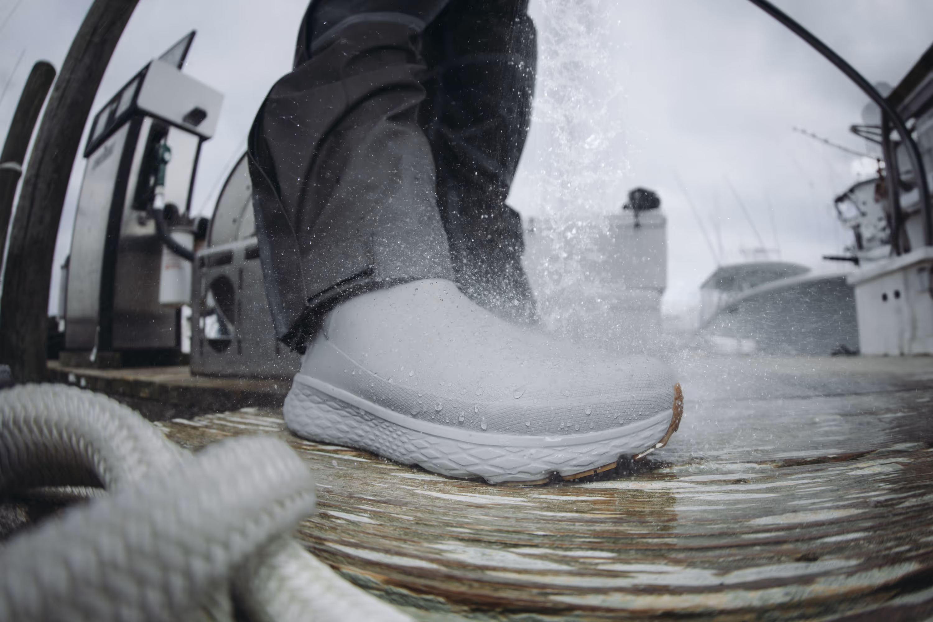 Folding knife with a blue handle and water droplets on the blade, lying on a table next to two fishing flies.