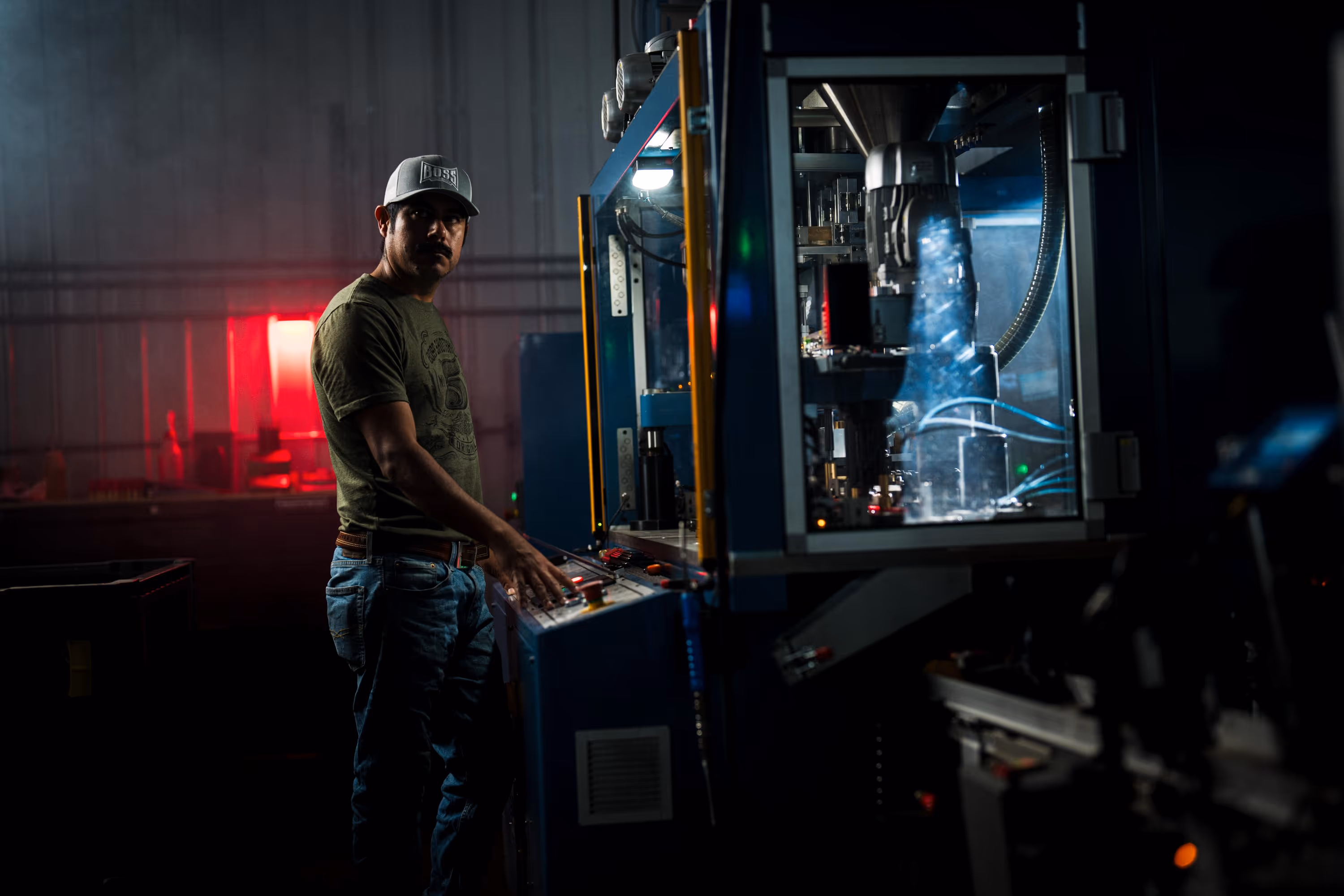 Two people wearing camouflage jackets and waders standing back-to-back in shallow water, one holding a fishing rod and the other a camouflaged rifle.