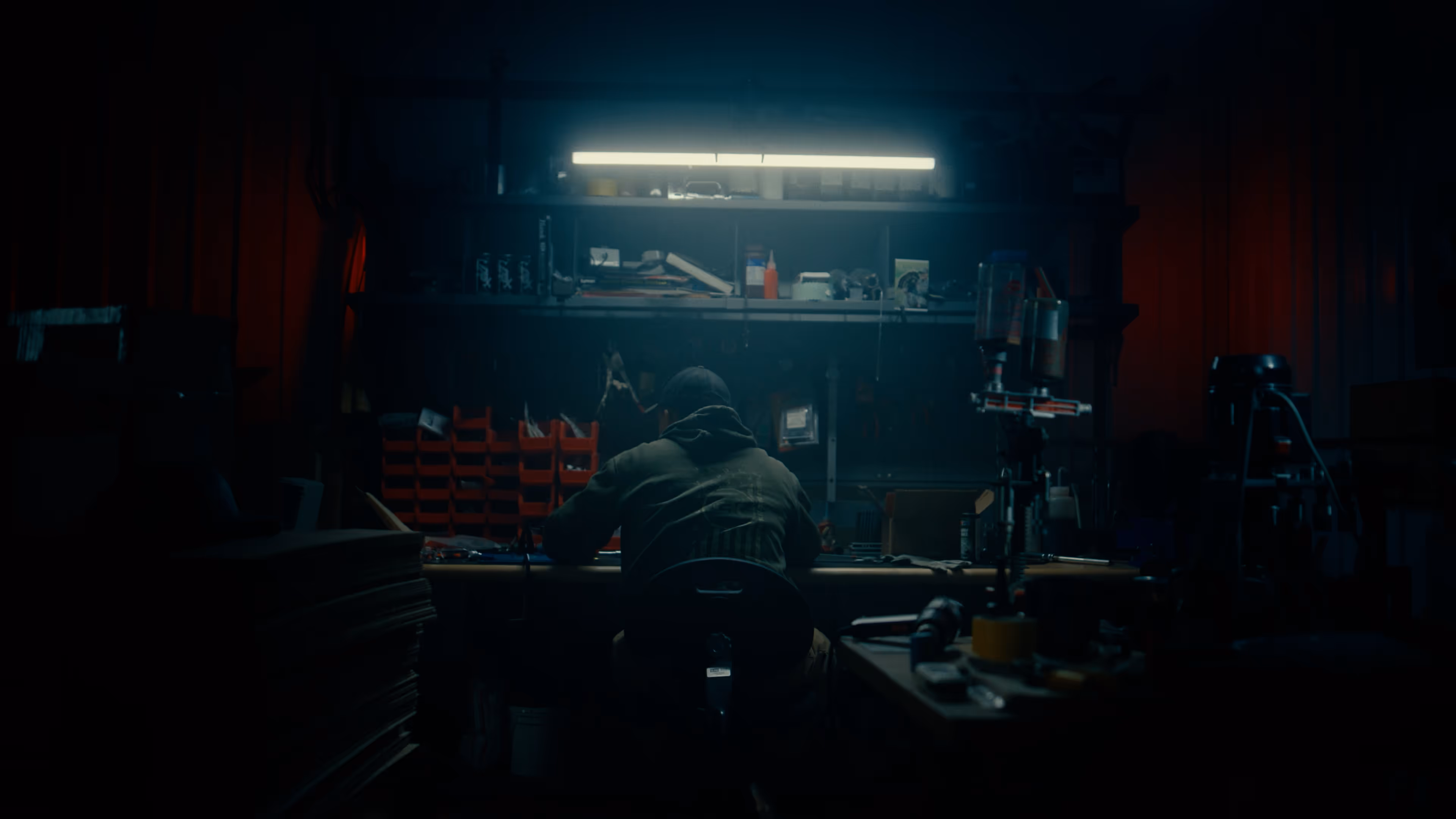 Man sitting at a work bench with his back to the camera