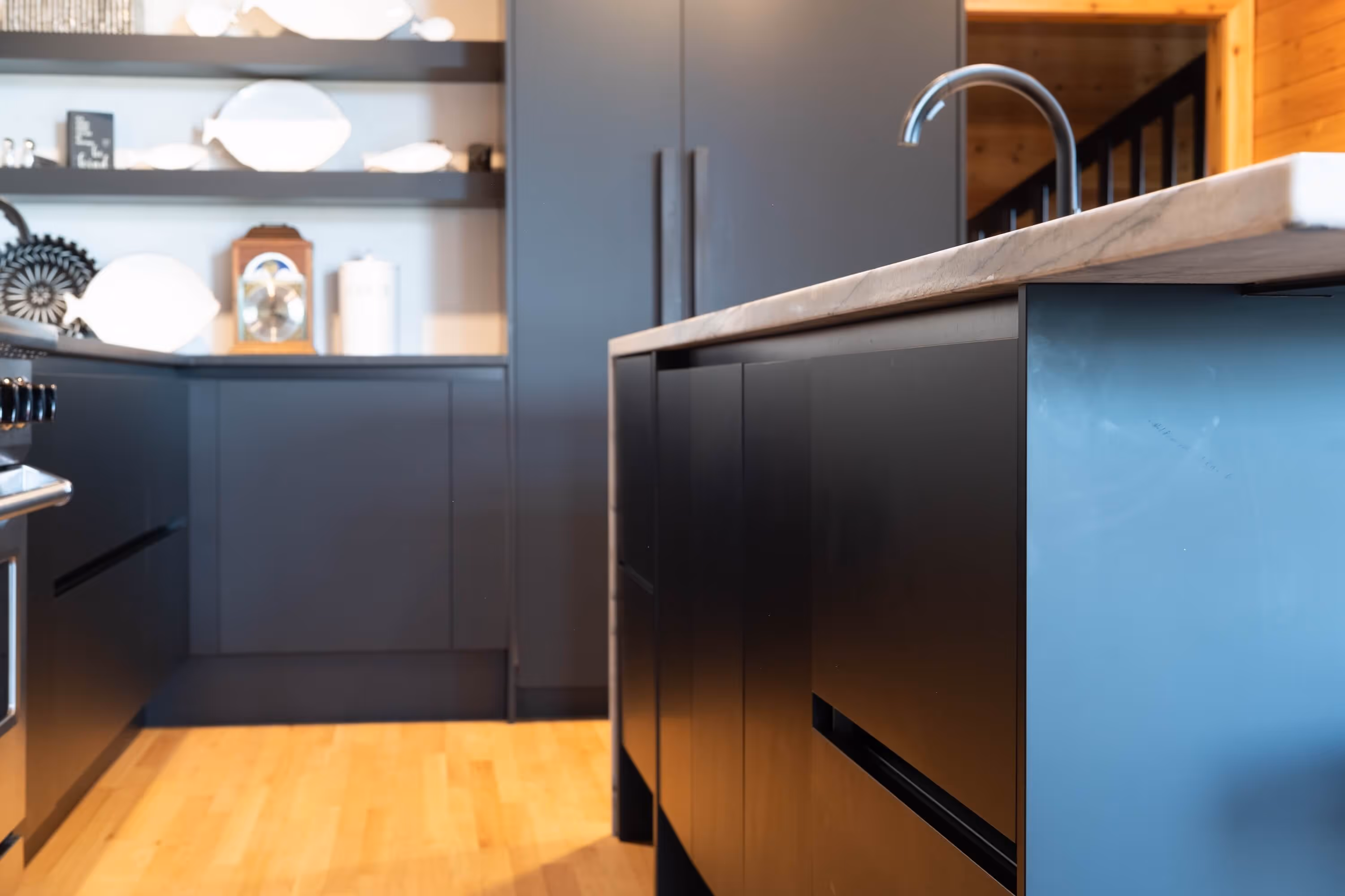 Modern kitchen featuring white upper cabinets, dark lower cabinets, hexagonal tile backsplash in shades of gray and white, and a stovetop with a wooden-accented range hood.