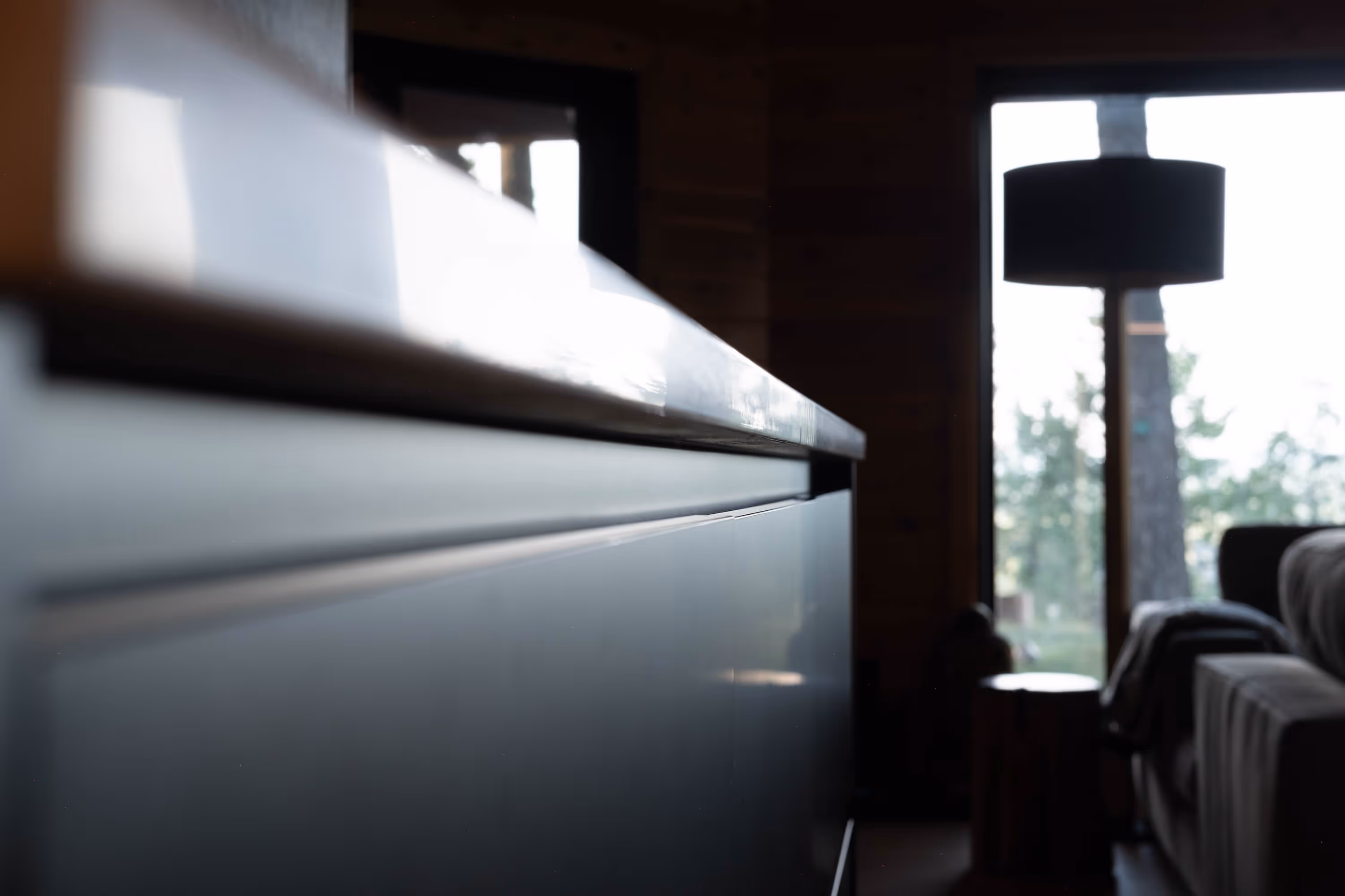 Close-up of a modern kitchen island countertop with a blurred living room and large window in the background.