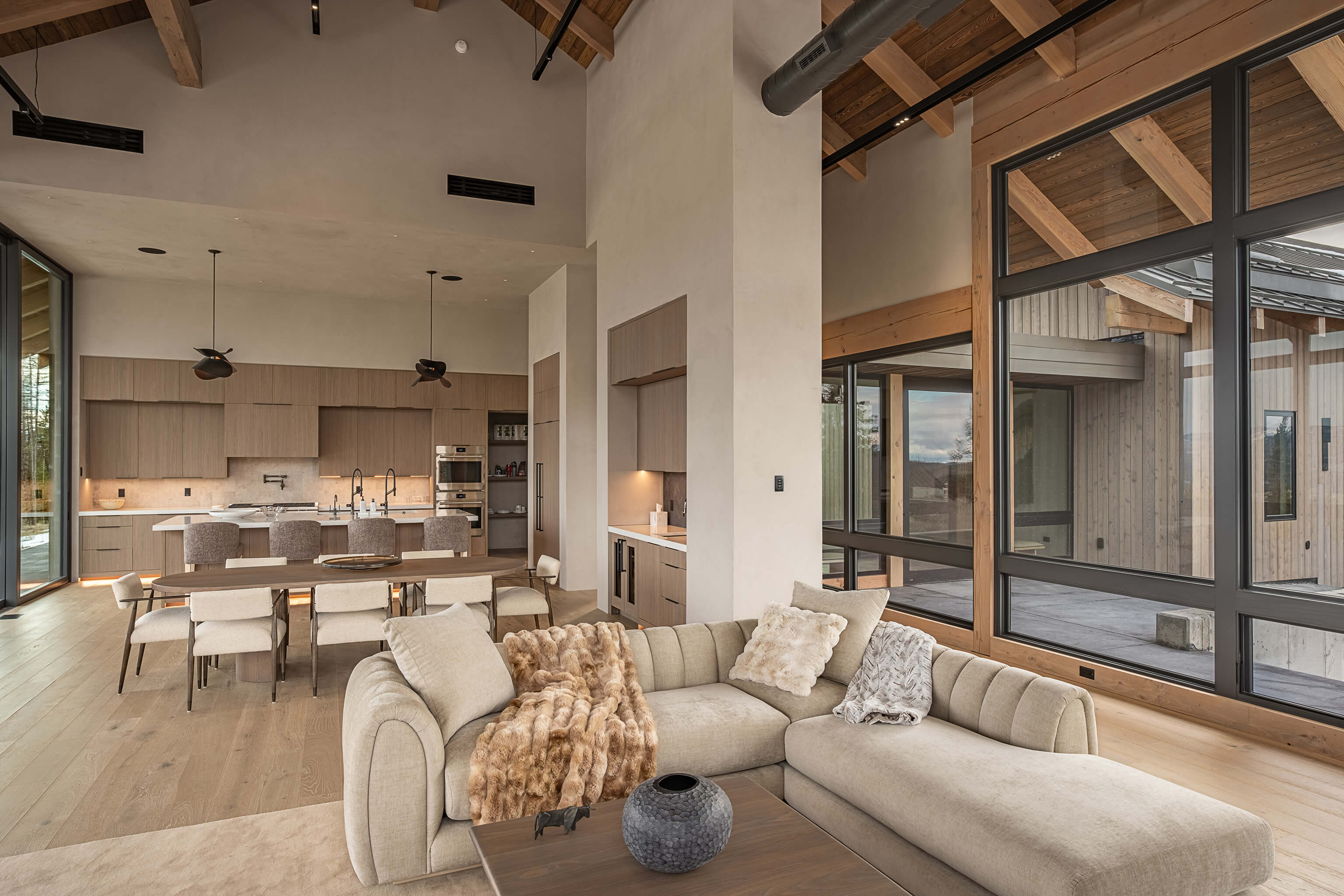 Modern kitchen with light wood cabinets, stainless steel gas stove, white countertops, and marble soap dispensers by the sink.