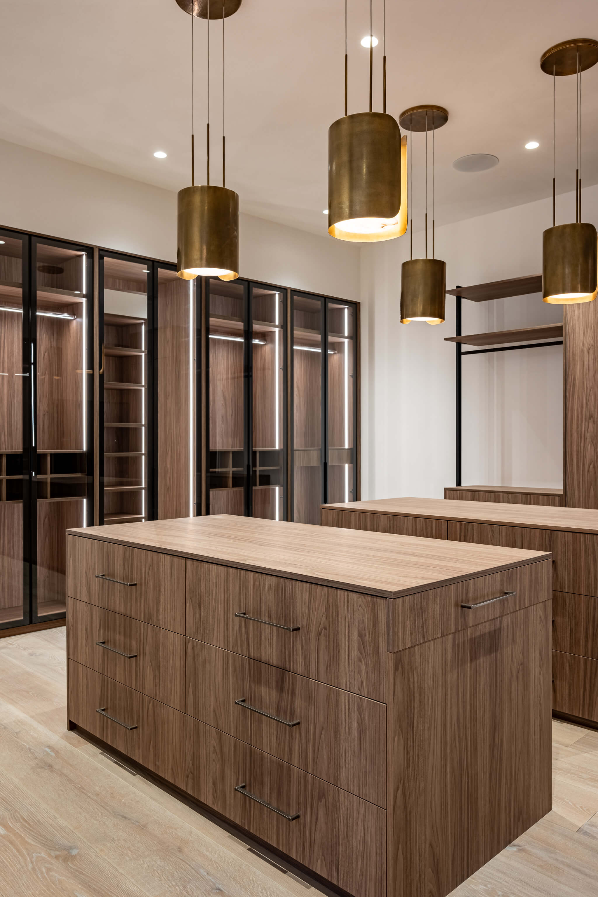 Modern kitchen sink with a curved faucet set in a concrete countertop beside large windows showing an outdoor wooded scene.