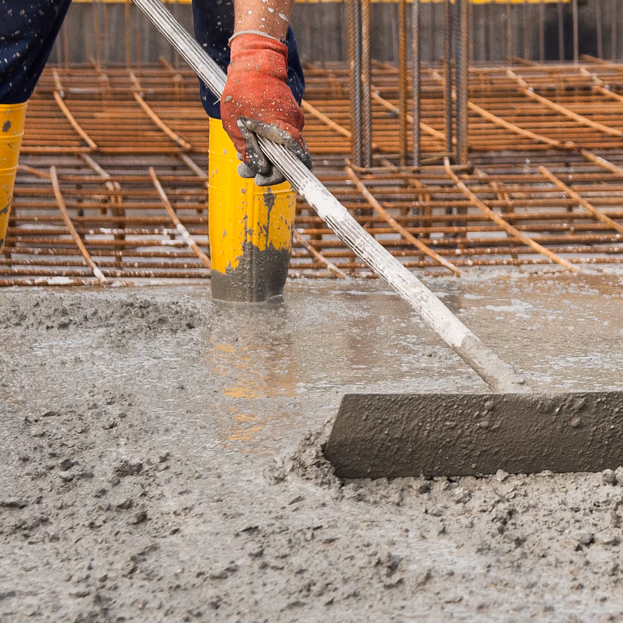 A worker spreading concrete during a slab pour