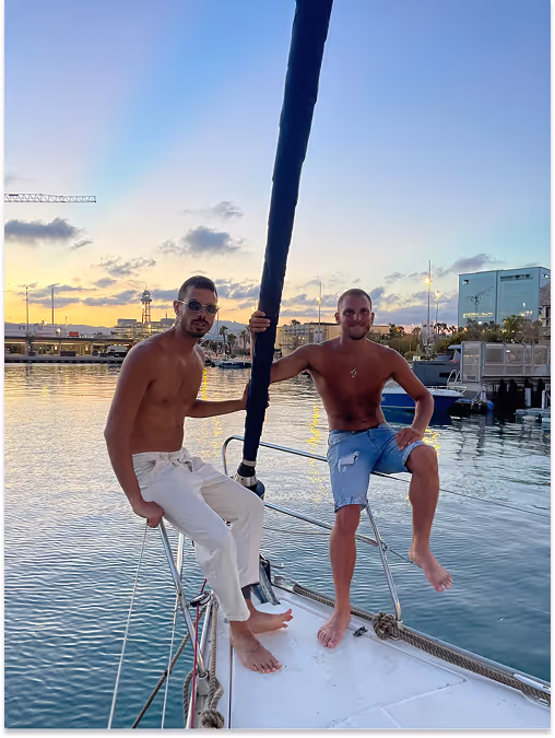 2 people in the front of a sailboat in port marina vela