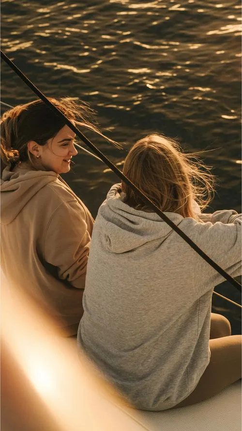 Friends relaxing on a sailboat during a peaceful Barcelona sunrise