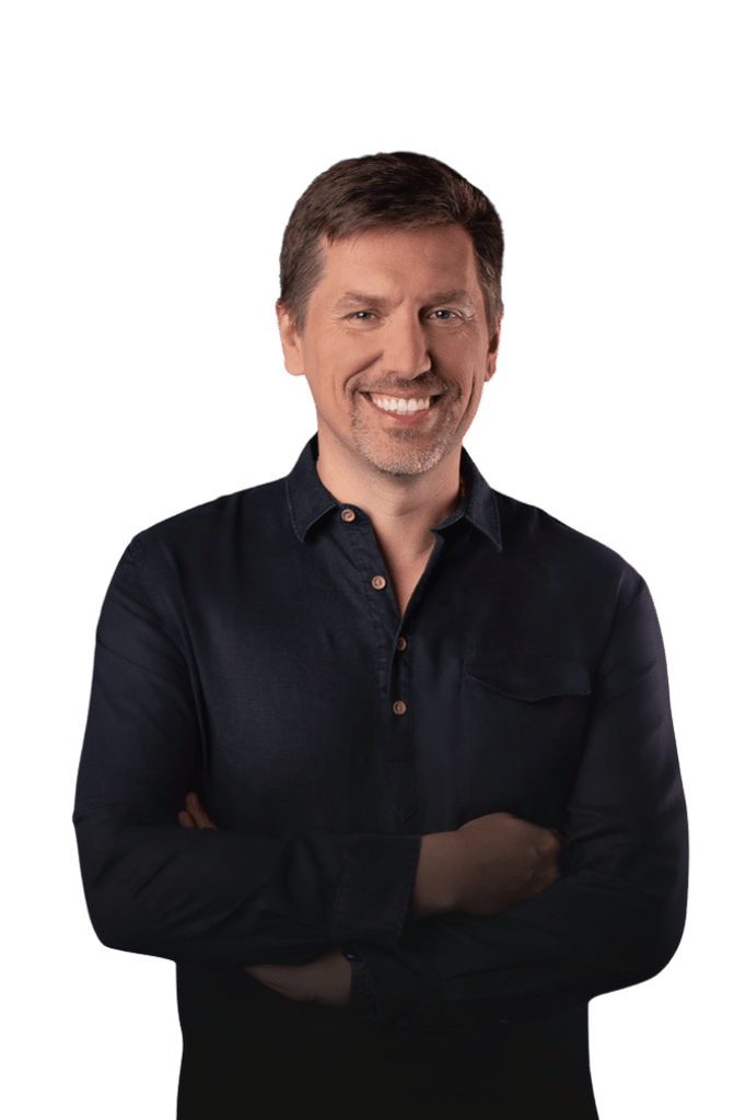 dr Paweł Kowalski z krótkimi brązowymi włosami, uśmiechnięty, ubrany w ciemną koszulę, z rękami założonymi na piersi.