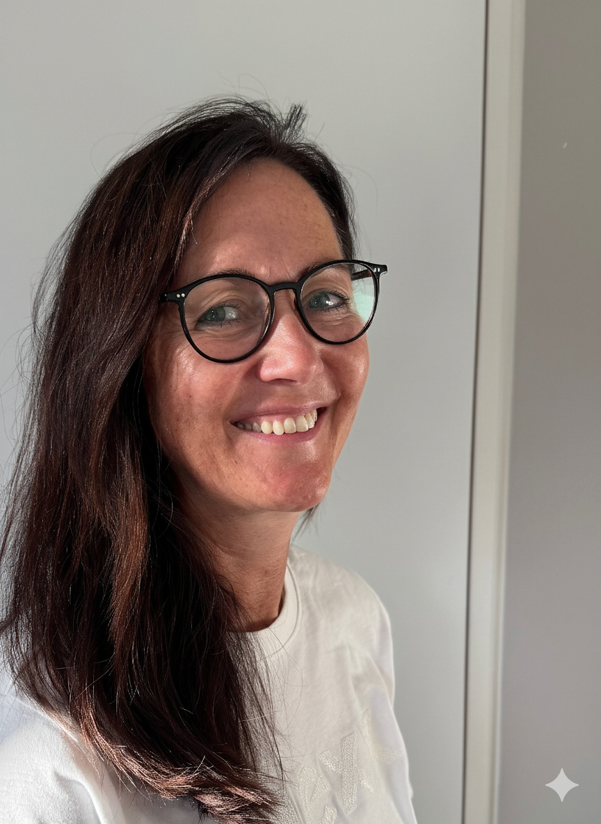 Smiling woman with long dark hair and black-rimmed glasses wearing a white shirt.