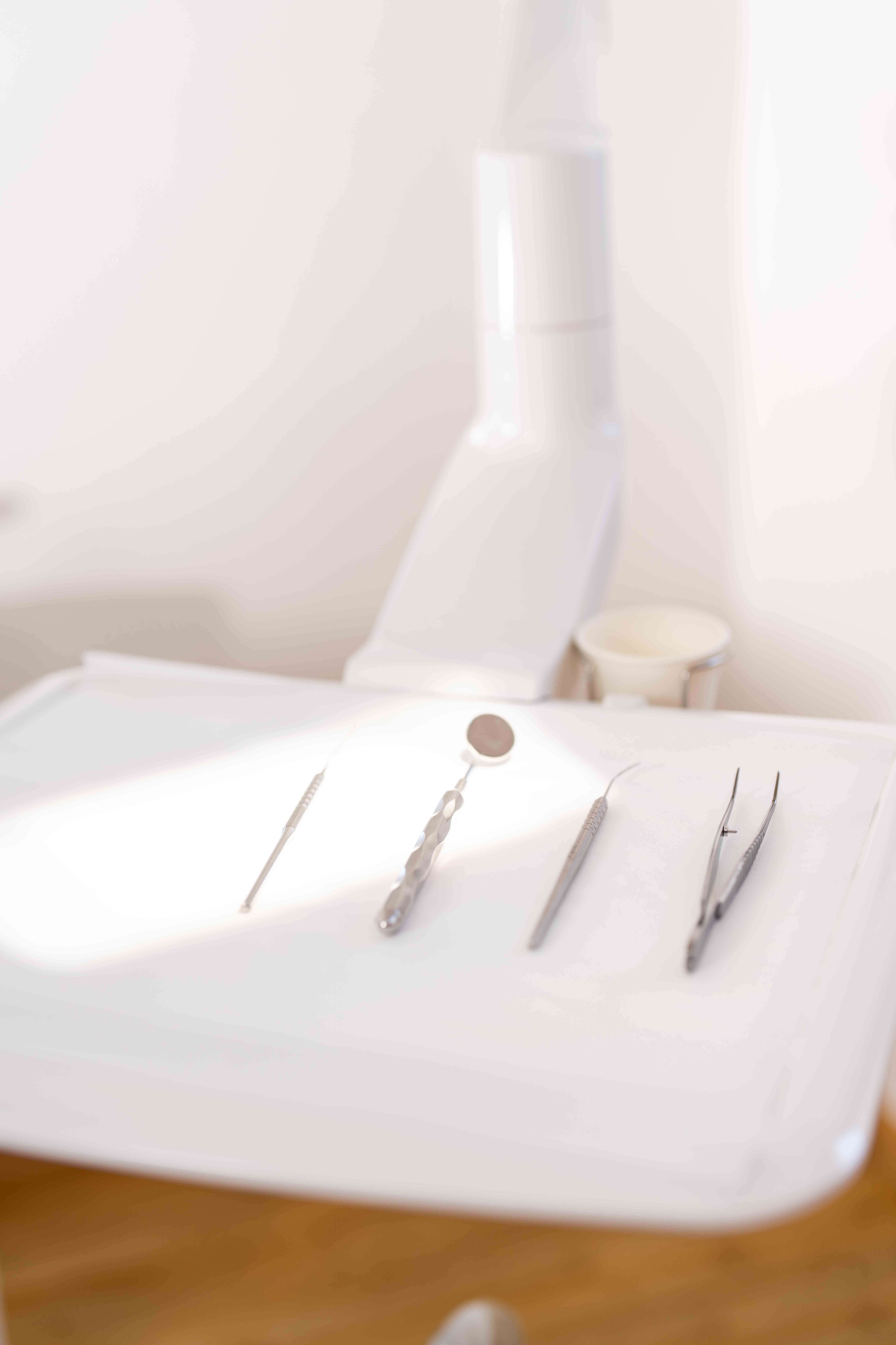 Four dental tools arranged on a white tray in a dental clinic setting.