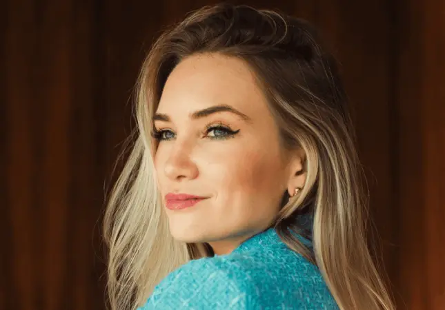 Woman in her 40s experiencing perimenopause or menopause symptoms, wearing turquoise sweater in natural light