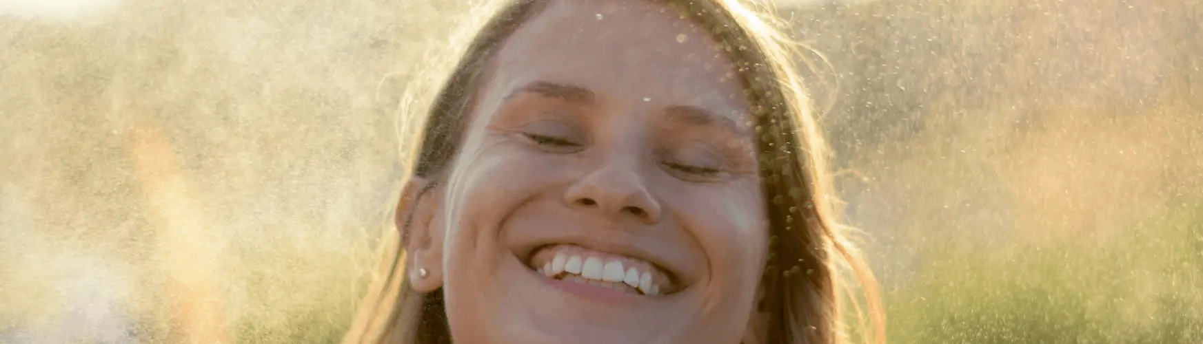 Woman smiling in natural sunlight representing wellness during perimenopause and menopause