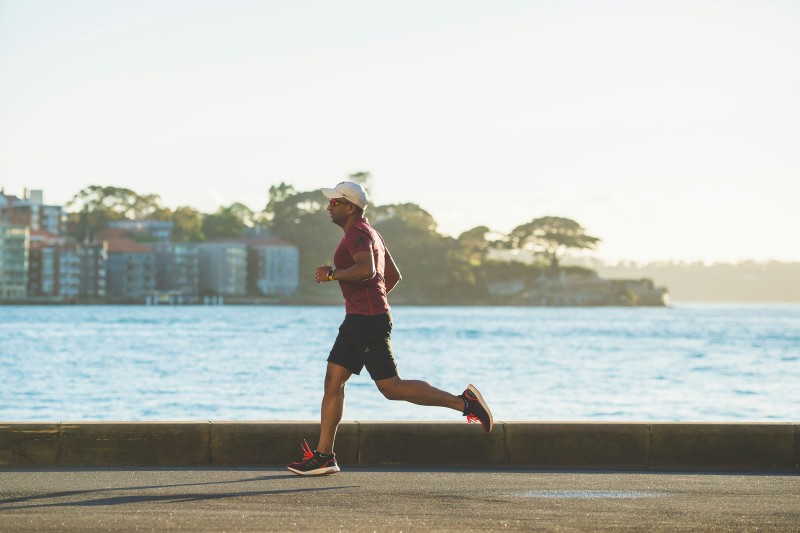 Ein Mann, der entlang einer Uferpromenade läuft und körperliche Aktivitätsniveaus repräsentiert, die häufig mit VO2Max korrelieren.