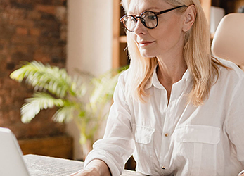 Woman With Glasses Sitting in Chair in Office Setting