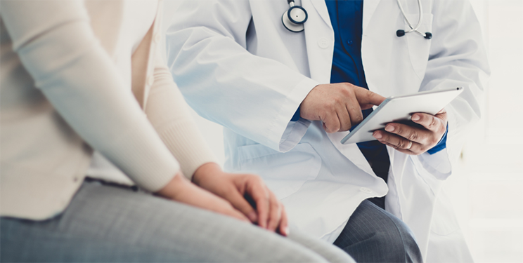 Medical Practice Employee Reviews Medical Information on Tablet with Patient
