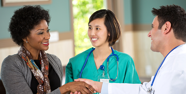Doctor shaking patient's hand at front desk