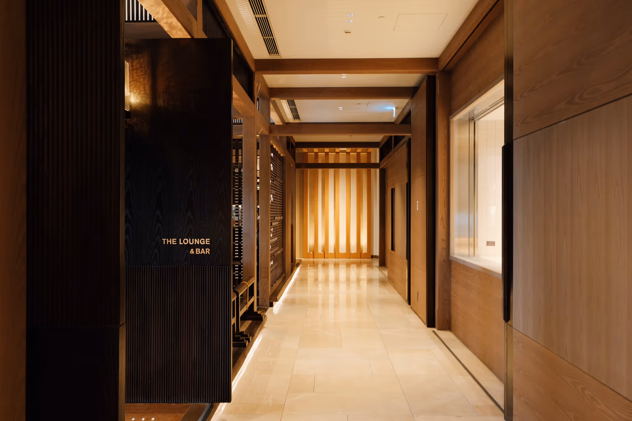 Well-lit corridor with wooden walls and a sign indicating the lounge and bar area on the left.