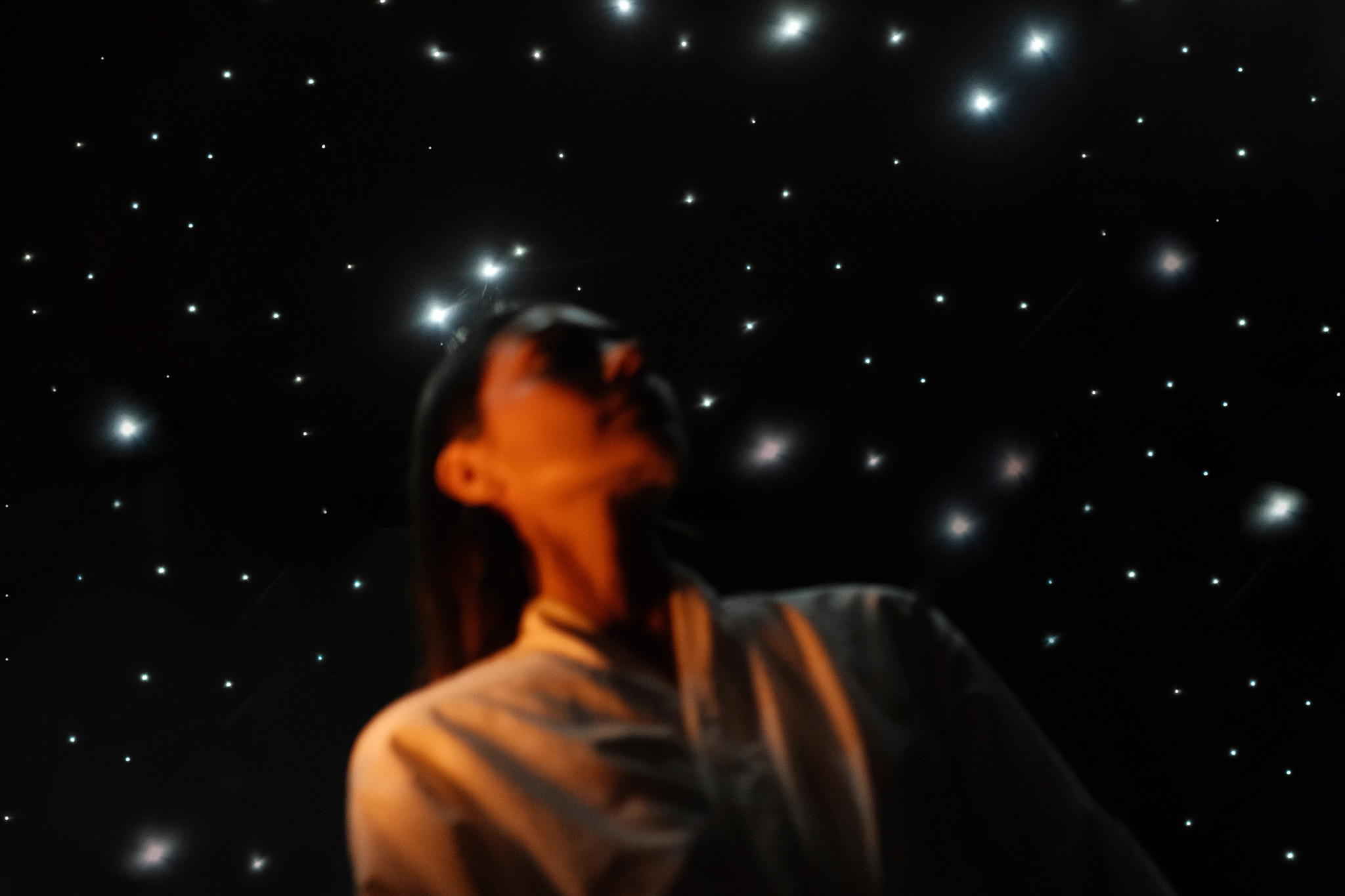 Two people standing on a fog-covered bridge over water, with trees and modern buildings in the background.