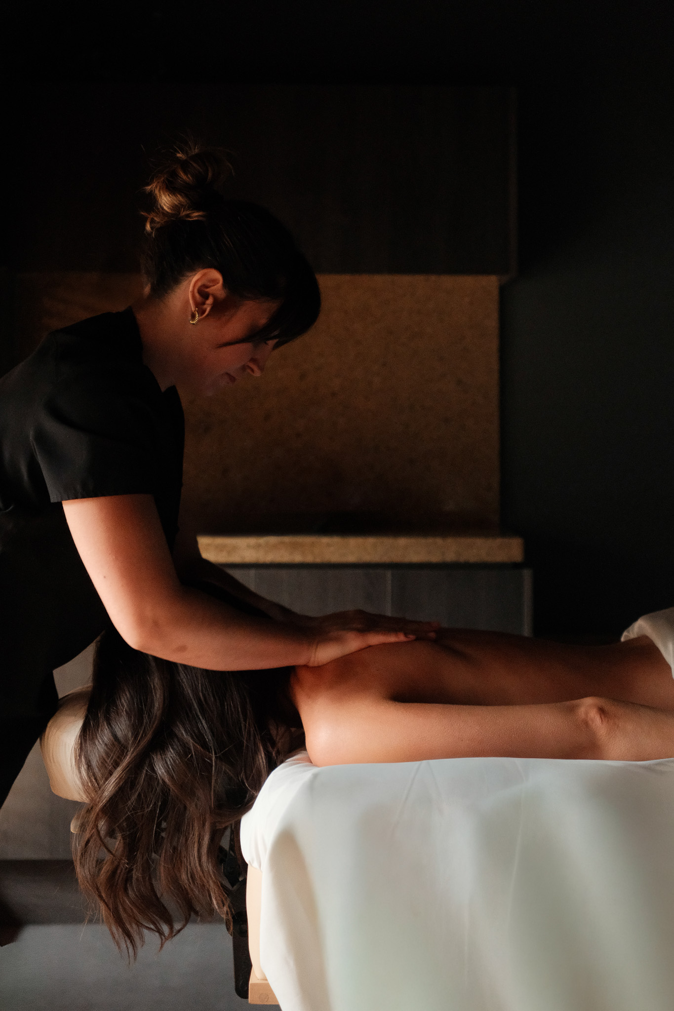 Man in sunglasses walking under a modern wooden pavilion with geometric roof beams and a building in the background.