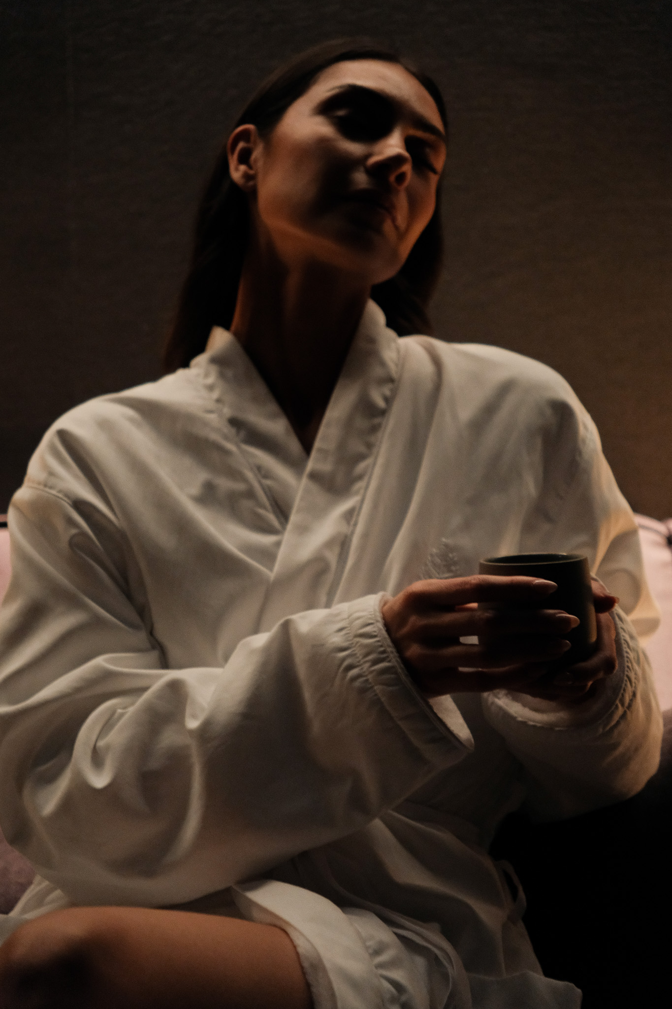 Koi fish swimming in a pond surrounded by dense green plants and a stone pathway with a wooden bridge.