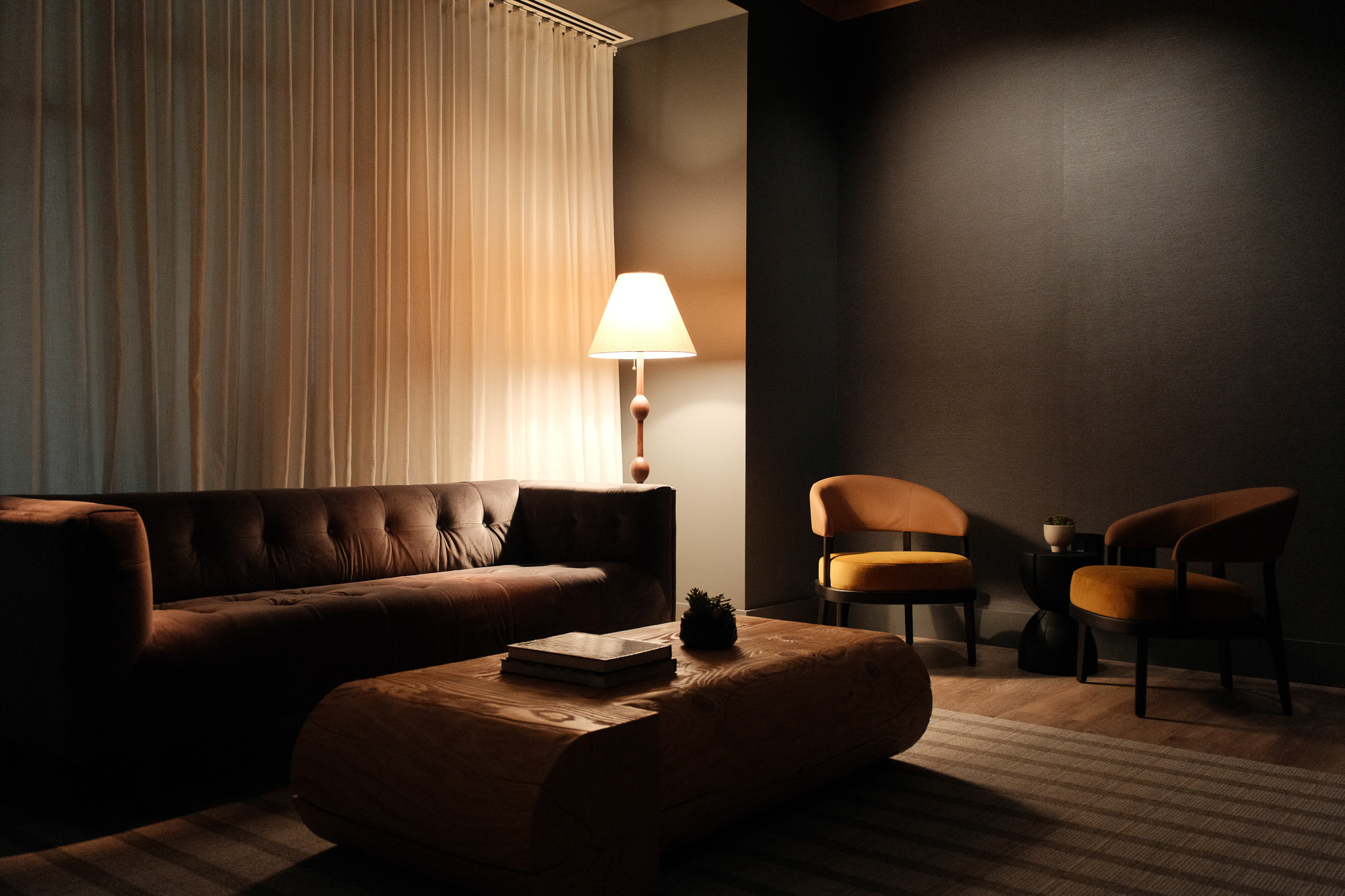 Koi fish swimming in a pond surrounded by dense green plants and a stone pathway with a wooden bridge.