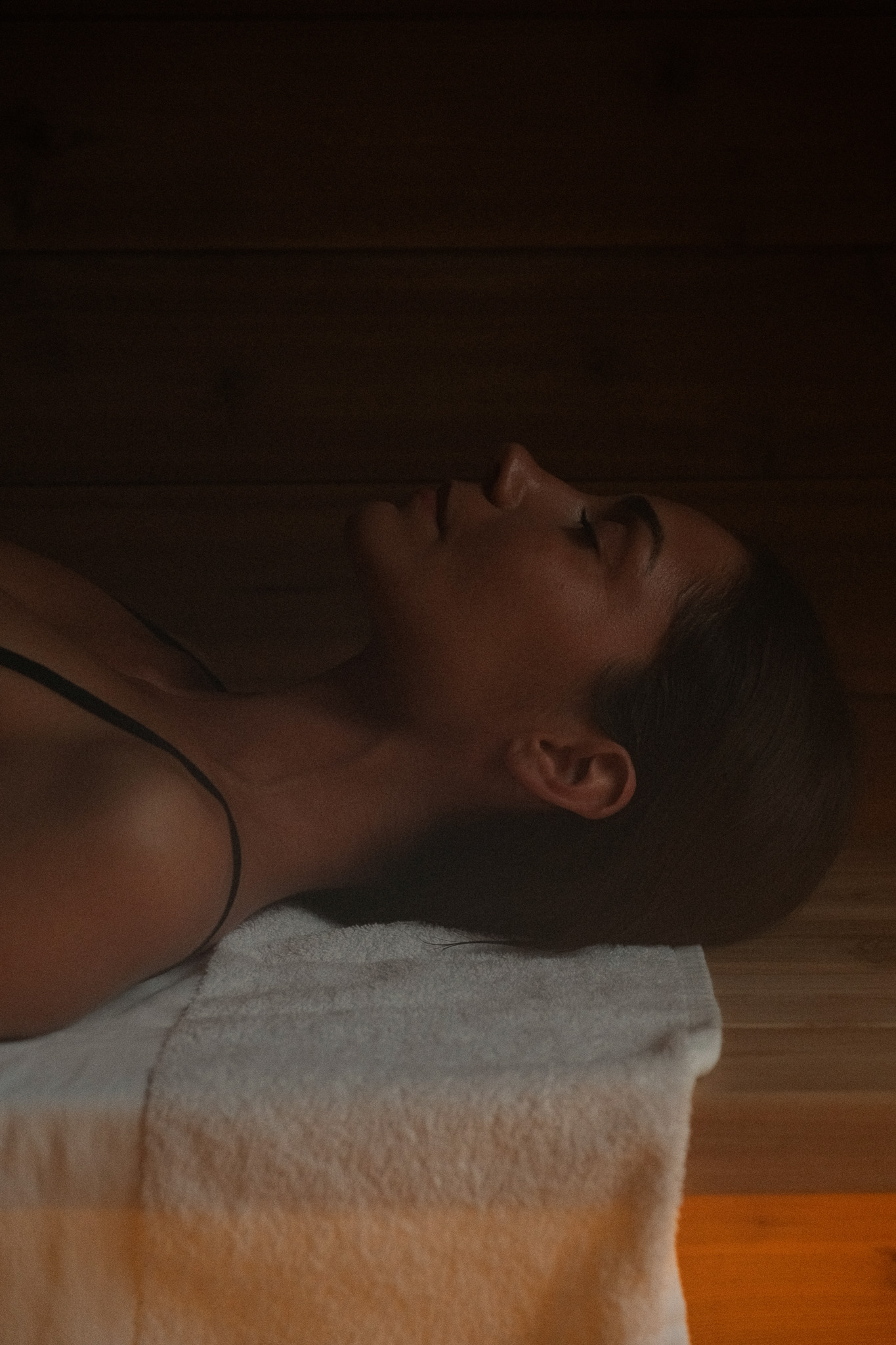 Koi fish swimming in a pond surrounded by dense green plants and a stone pathway with a wooden bridge.
