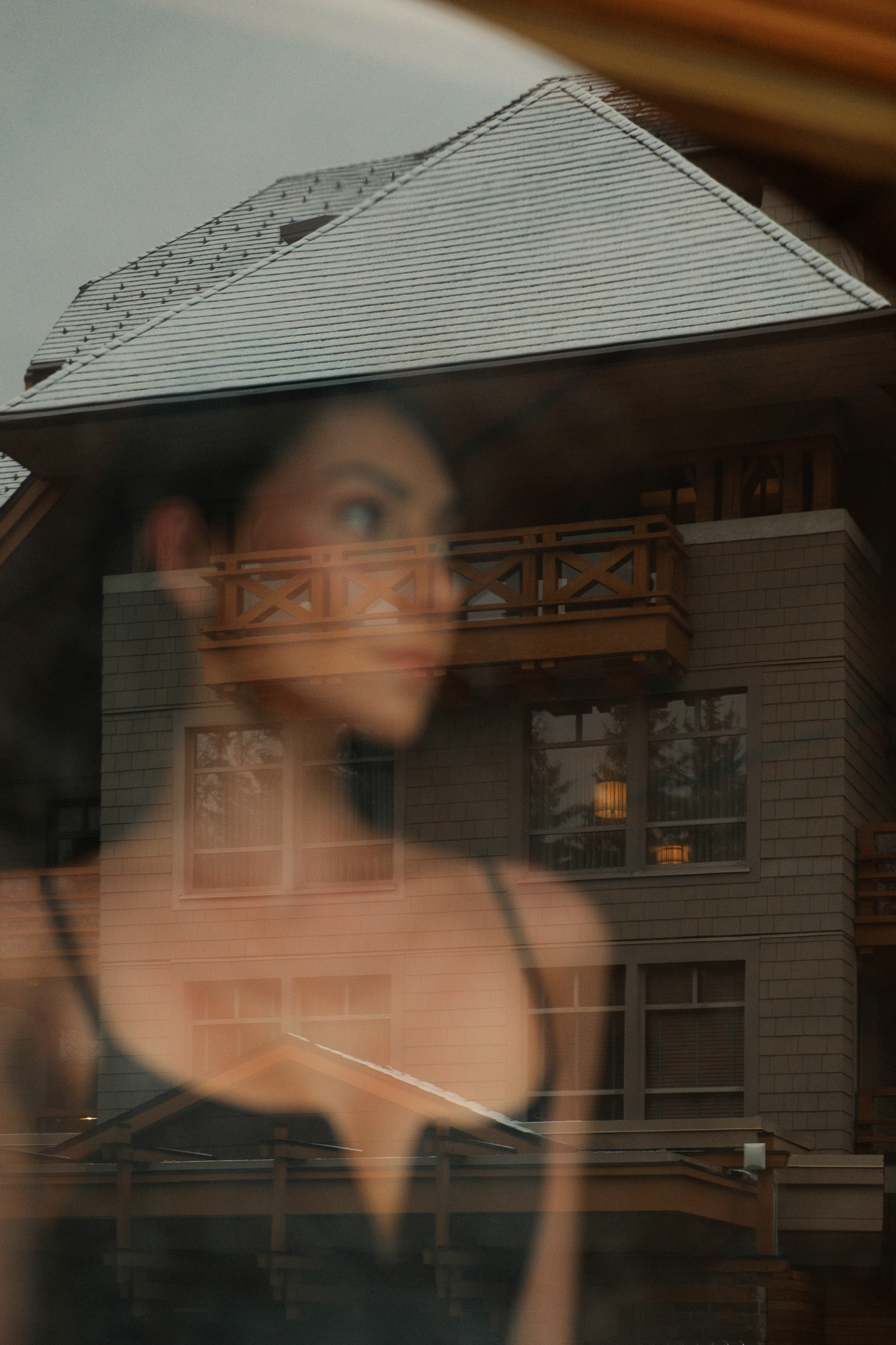 Modern building with large windows behind a calm pond surrounded by autumn foliage and misty rocks.