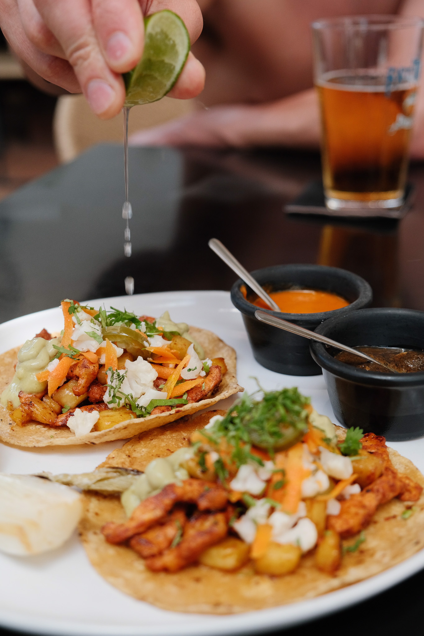 Hand holding a cocktail glass with a yellow flower garnish near a swimming pool with an inflatable float in the background.