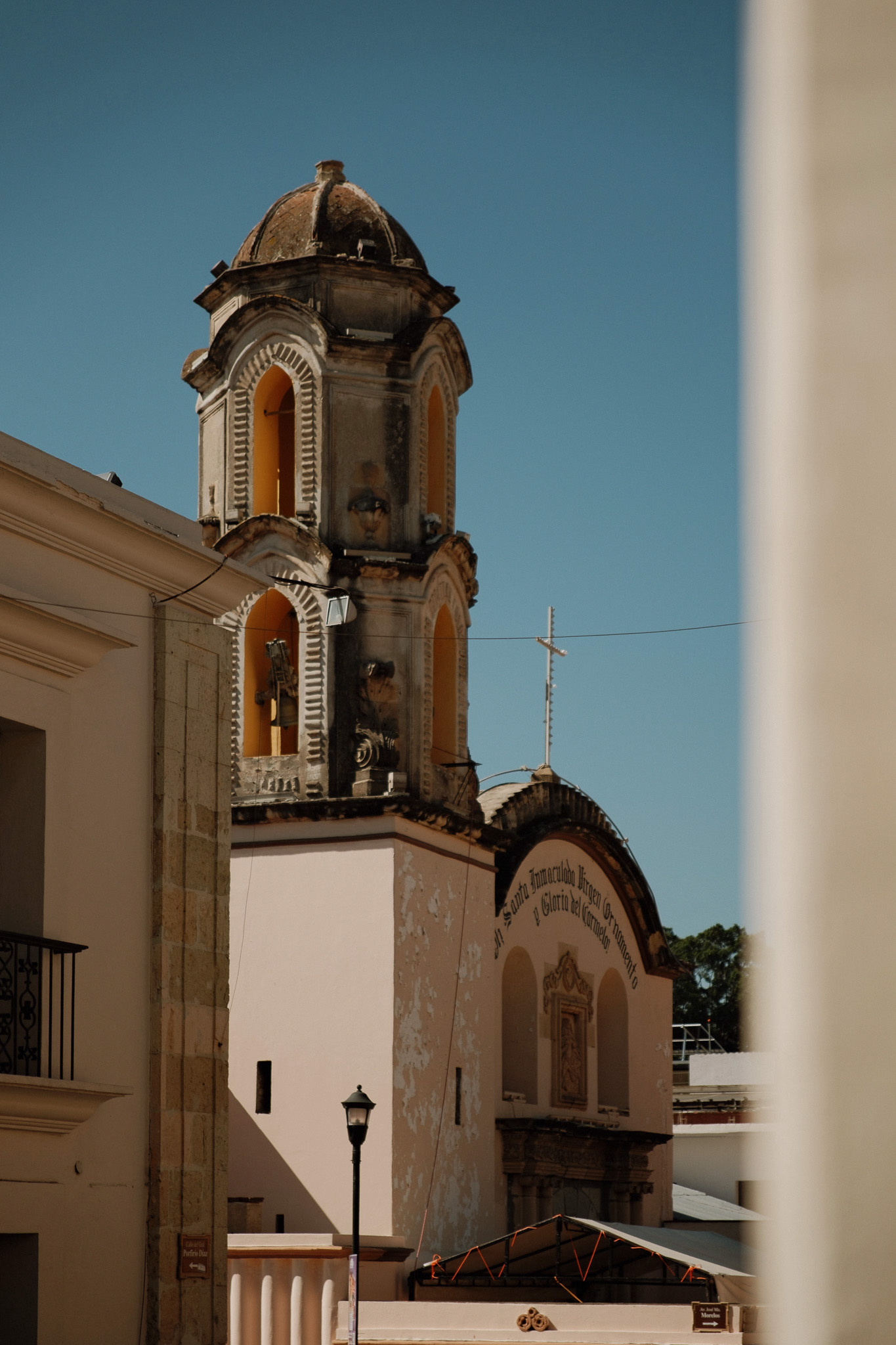 Old church tower with arched windows and dome against clear blue sky in daytime.