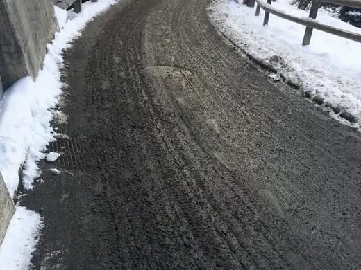 Weg zwischen verschneiten Mauern, Fahrbahn voller Matsch