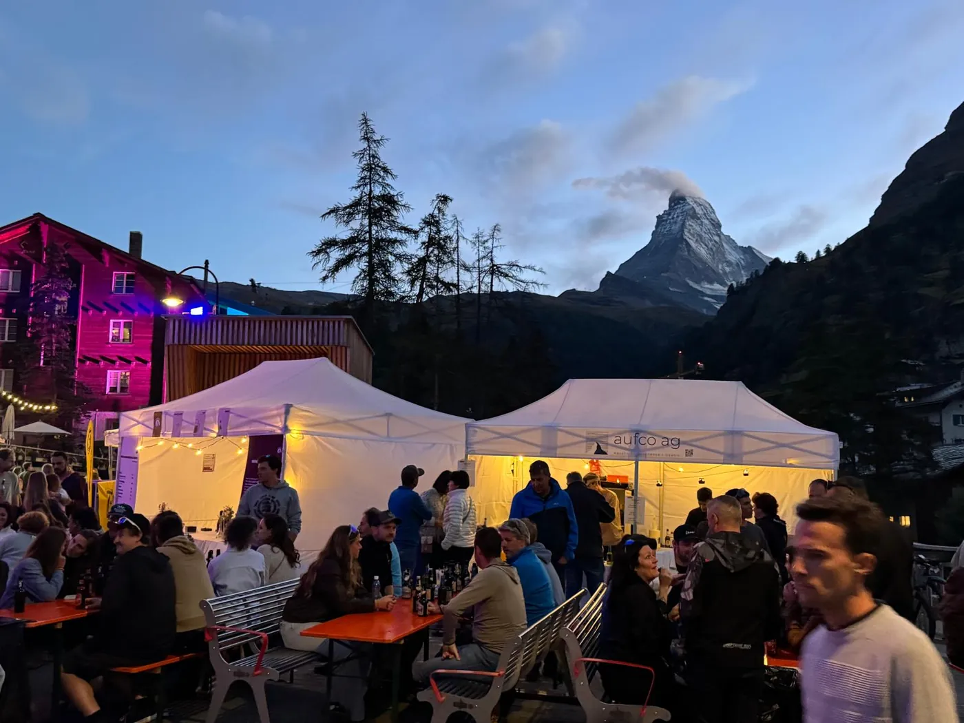 Zelte und Biertische in der Dämmerung, dahinter das Matterhorn