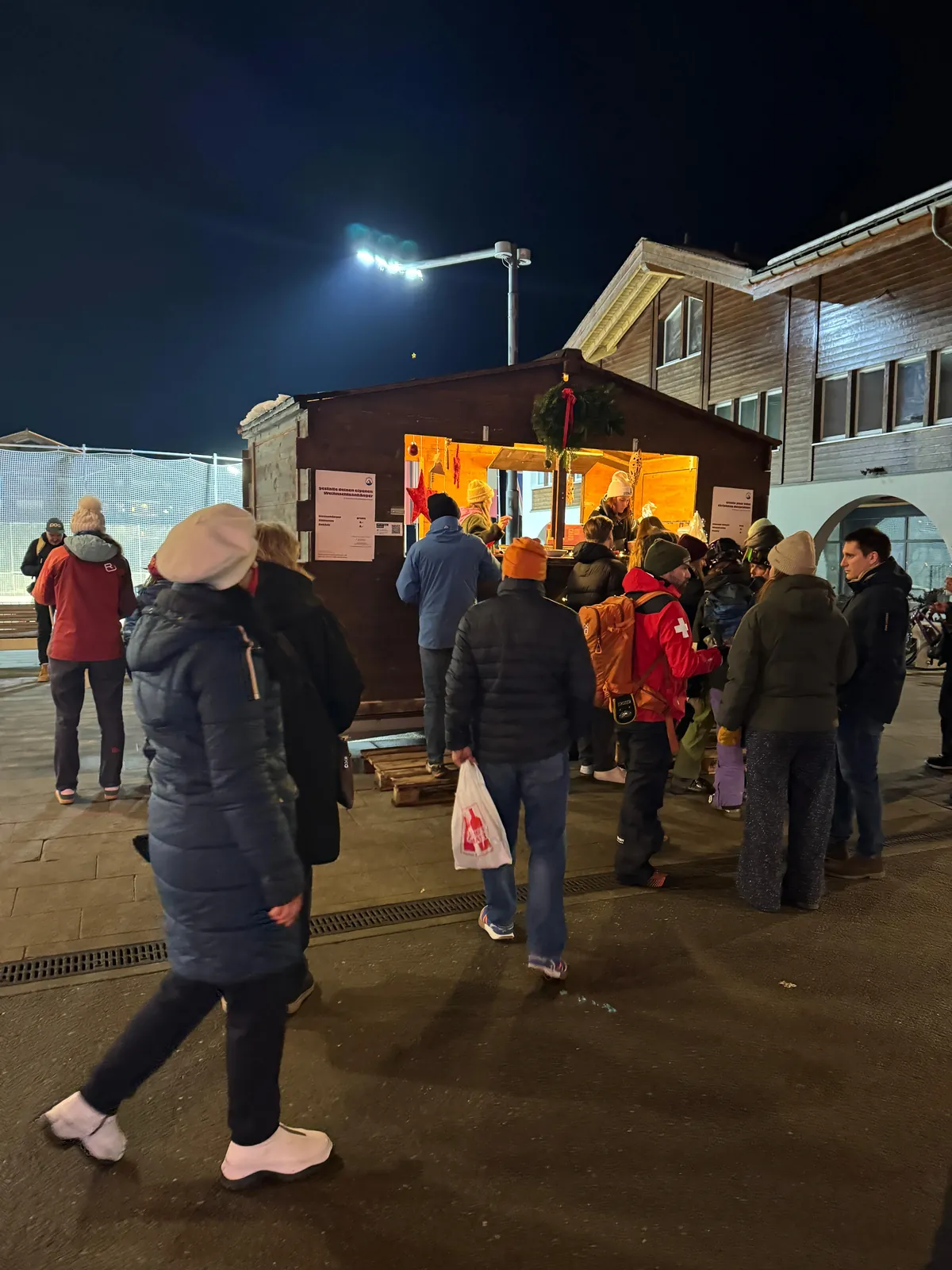 Menschen vor dem beleuchteten Eventschalet am Abend