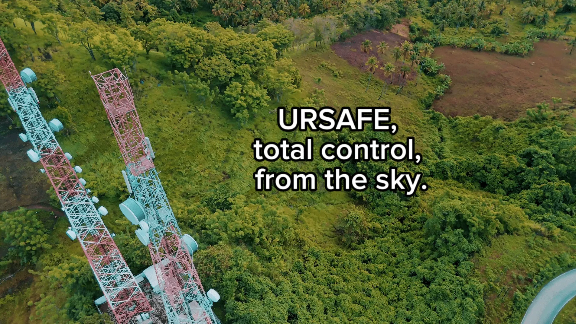 Two tall telecommunications towers with antennas surrounded by dense green trees and vegetation, with text reading 'URSAFE, total control, from the sky.'