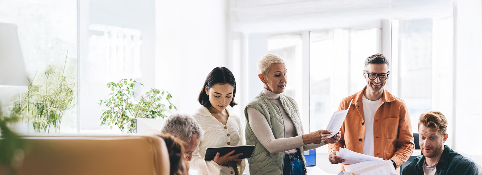 A team of people discussing finance reports using paper printouts and technology