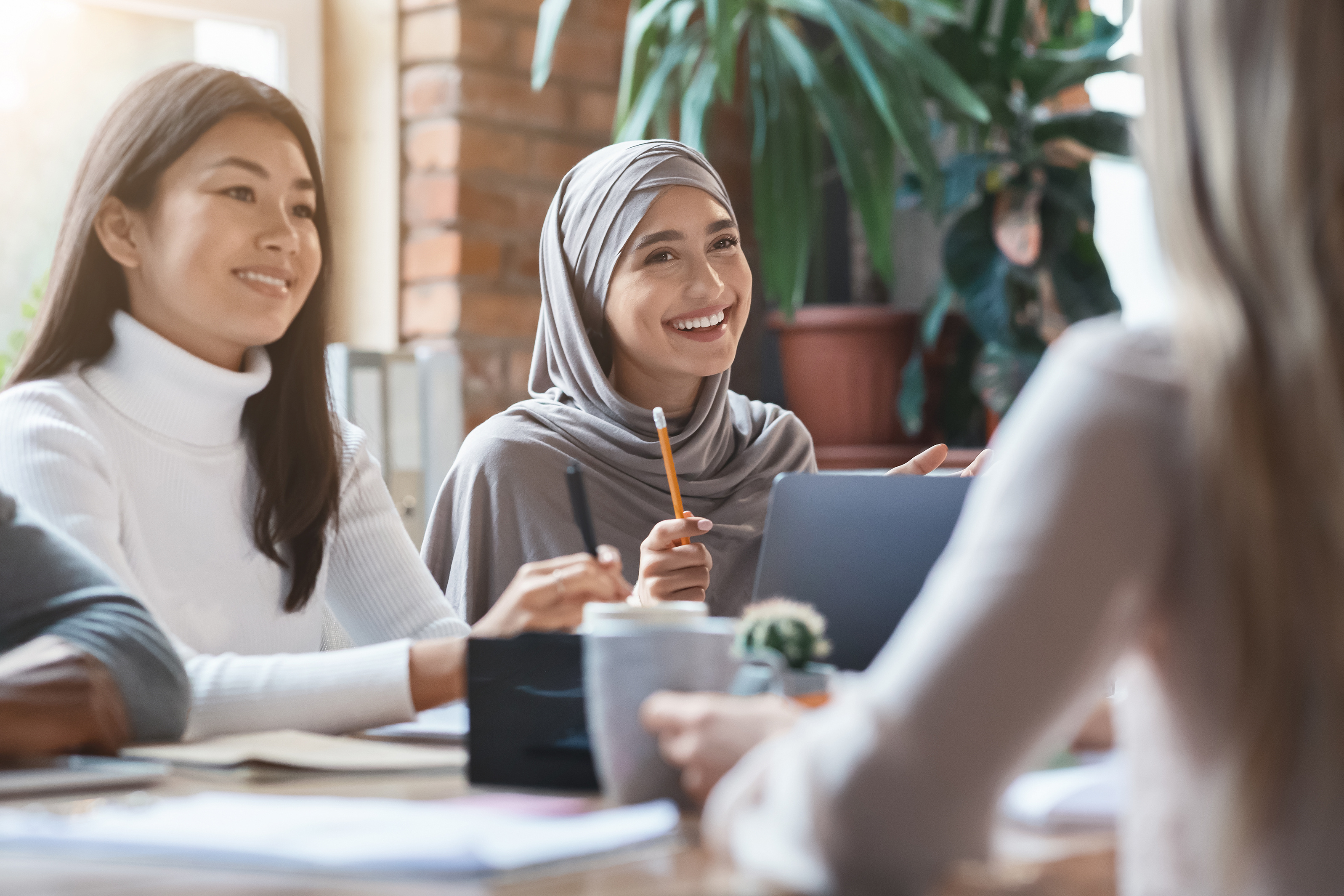 Diverse group of women at a conference table smiling
