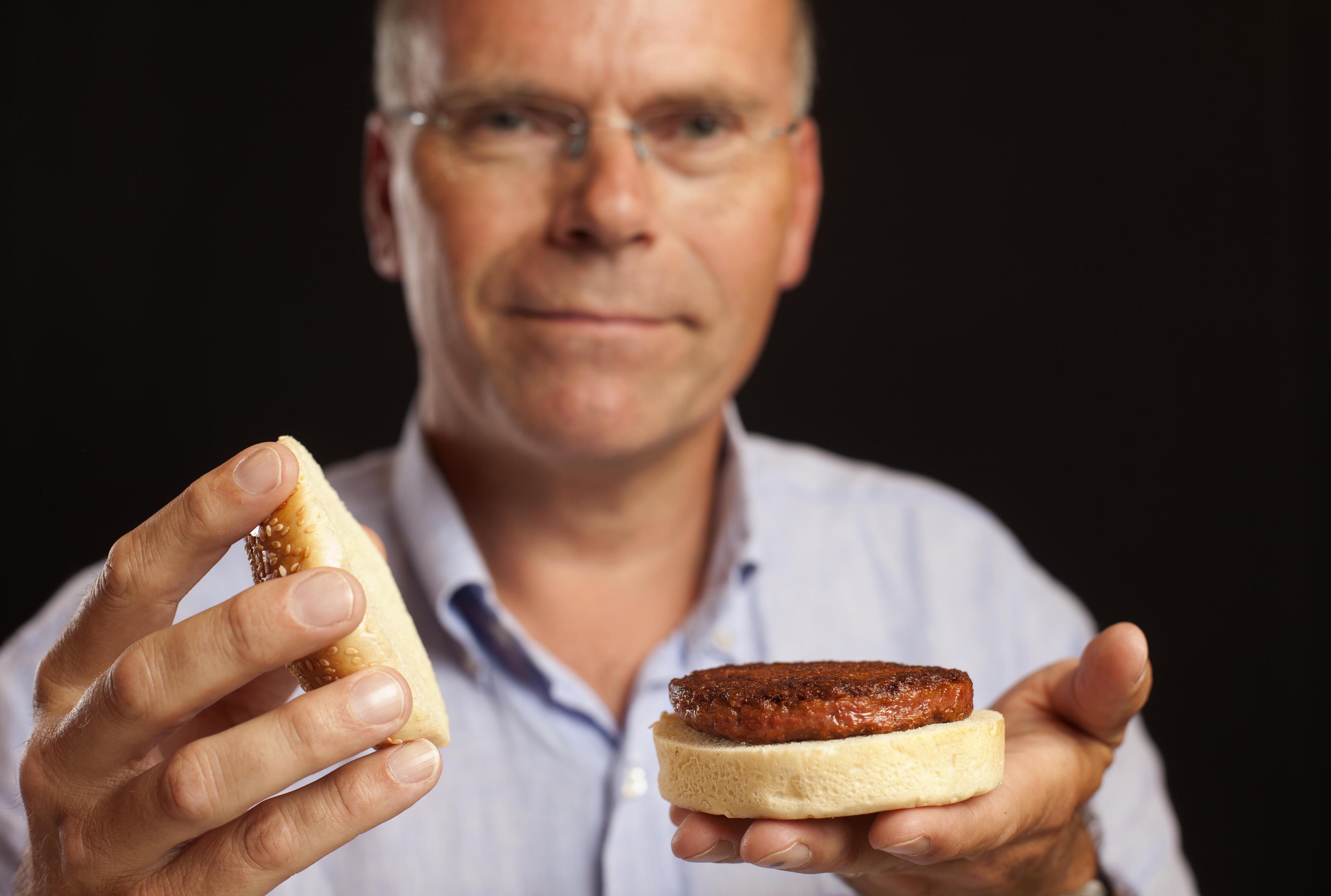 Mark Post with the first cell-cultured hamburger in 2013 ("Mark Post with the first cell-cultured hamburger" by Kaasterly / CC BY 4.0 via Wikimedia Commons)
