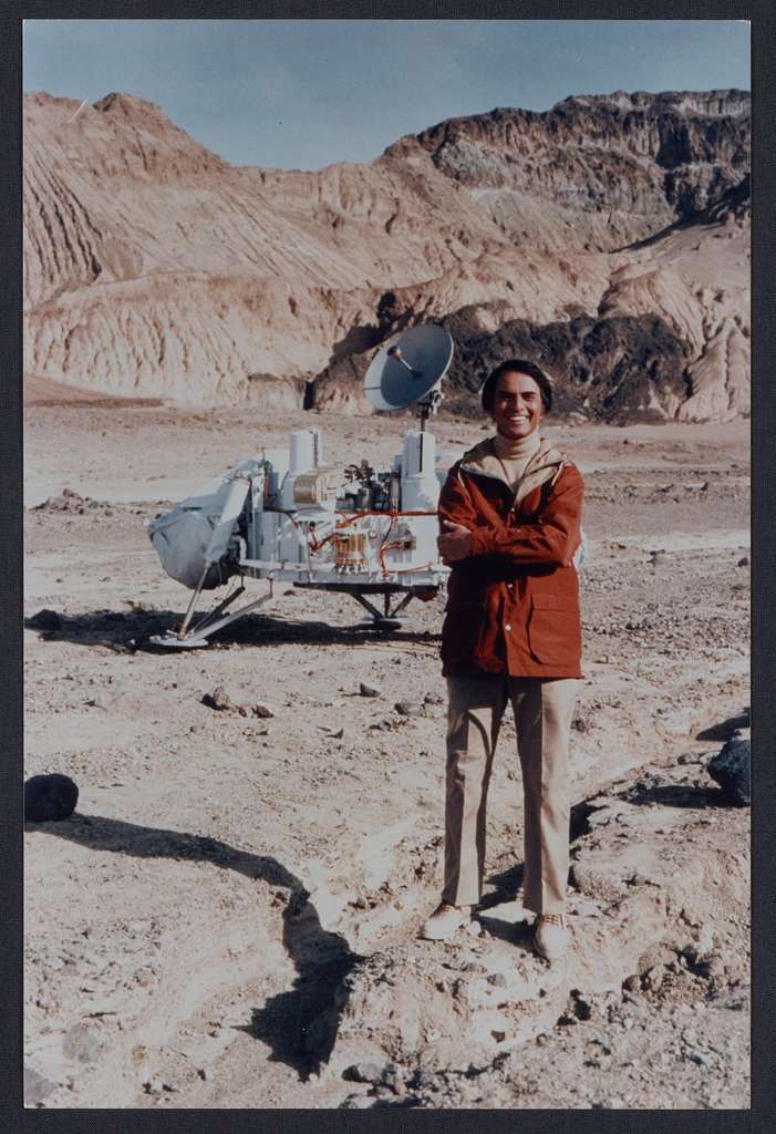 Carl Sagan next to a model of a NASA Viking landers, which used three legs to land