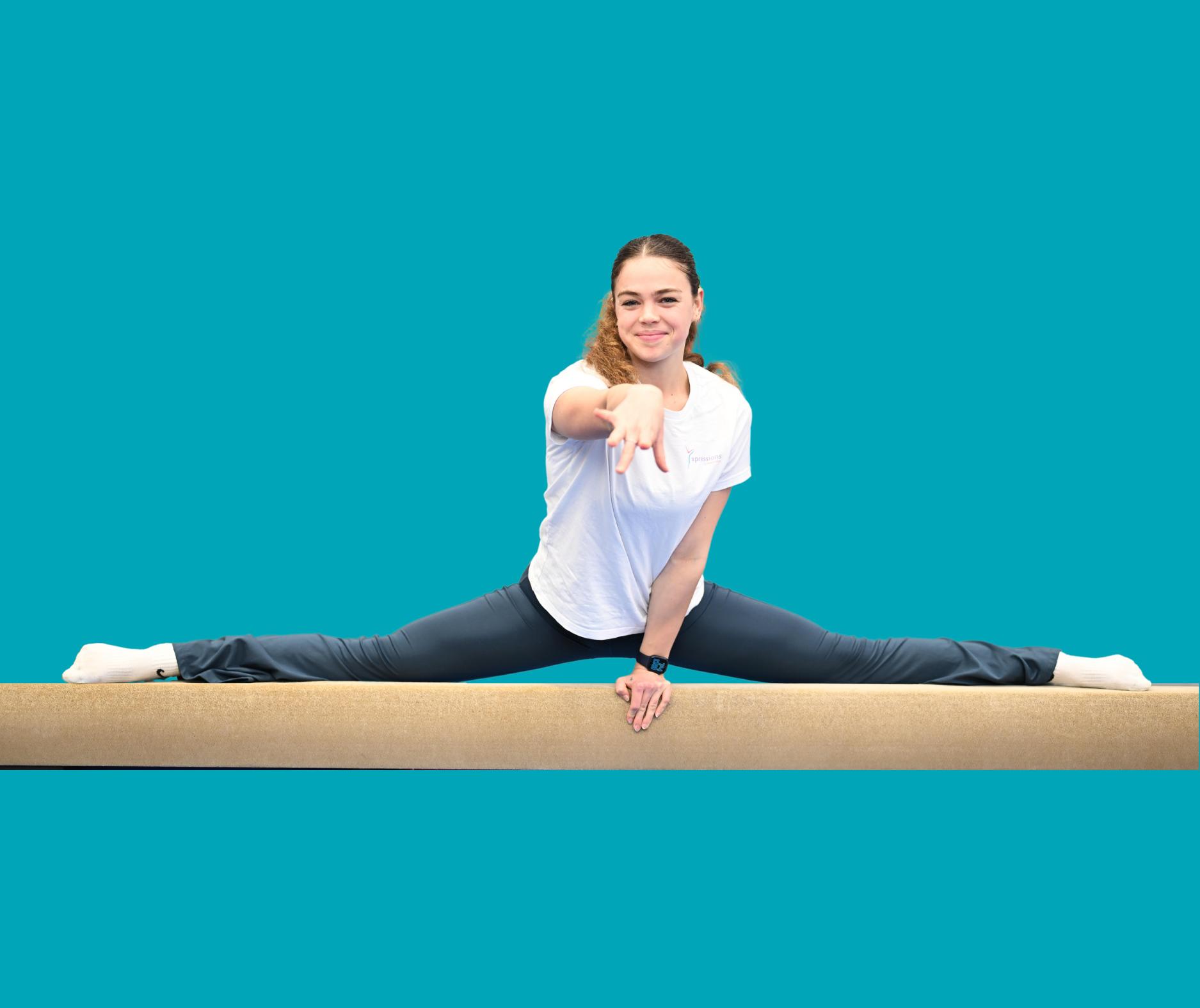 Young woman in white shirt does a split on a balance beam against a teal background.